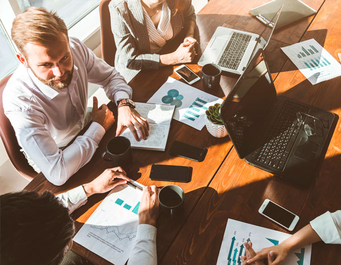 Reunión de trabajo con personas analizando gráficos y documentos.